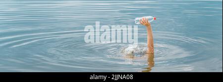 Raised hand holding bottle plastic garbage beach pollution water environment and plastic concept. Save ocean plastic pollution. Cleaning trash water Stock Photo