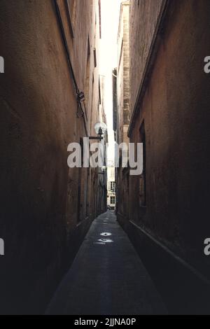 A vertical shot of a narrow street between buildings with painted ...