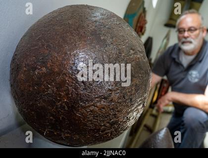 Mellenthin, Germany. 27th July, 2022. Robert Mollitor, head of the munitions salvage service in Mecklenburg-Western Pomerania, shows a 17th-century mortar ball found during construction work. The 28-cm caliber projectile weighs 68 kg and was filled with black powder. The Munitions Salvage Service is reportedly responsible for the disposal of all ordnance or explosive weapons of war. Credit: Stefan Sauer/dpa/Alamy Live News Stock Photo