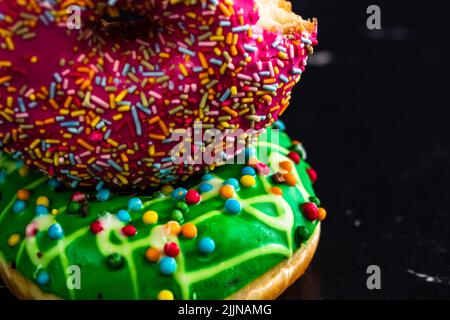 Glazed donuts with sprinkles isolated on a black background Stock Photo