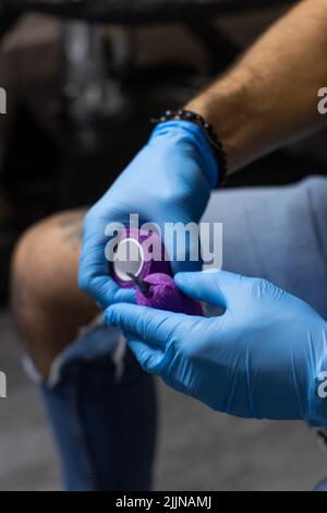 A closeup shot of male hands of a tattoo  artist preparing a tattoo machine before making a tattoo Stock Photo