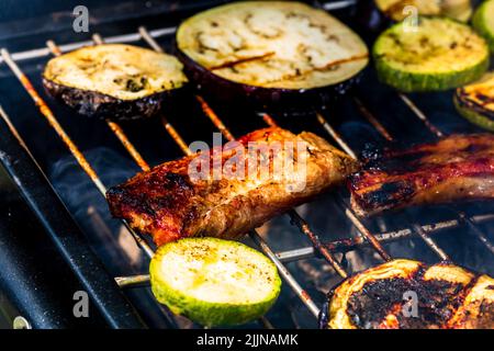 Grilling meat rolls called mici or mititei with vegetables on char barbecue Stock Photo