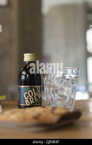 A closeup shot of Cold Brew coffee and a glass with ice cubes on a wooden table in a coffee shop in Novi Sad, Serbia Stock Photo