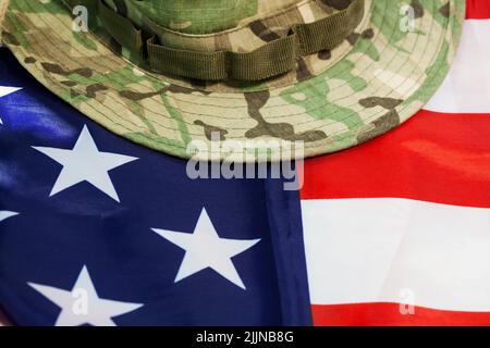 A closeup of US flag with camouflage cap combat hat Stock Photo