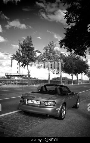 A vertical grayscale shot of a Roadster Mazda MX-5 car on a road in Courtrai, Belgium Stock Photo