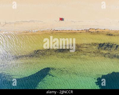 Aerial view of Paralia Issos beach in Corfu, Greece. Awning. Red beach tent. Bathers strolling on the water's edge Stock Photo