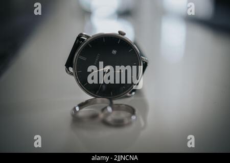 A close-up shot of a male hand watch next to some marriage rings. Stock Photo