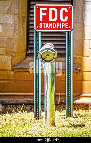 FDC Fire Department Connection Standpipe by old rock building - part of a fire sprinkler system and enables a responding fire department to supplement Stock Photo