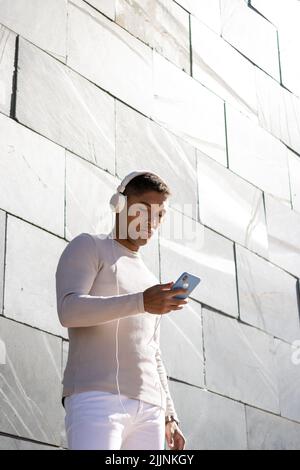 A Latin man enjoying listening to music through headphones with his phone Stock Photo
