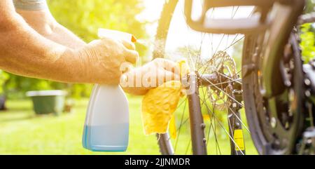 Senior man hand cleaning the bike by spray and rag, doing maintenance of his bicycle, sport concept Stock Photo