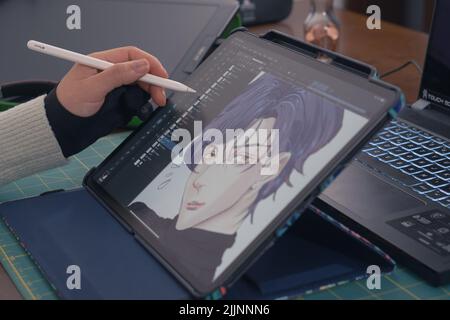 Young asian graphic designer working on computer and drawing digital tablet at office studio. Caserta, Italy, January 02th 2022. Stock Photo