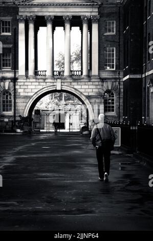 A vertical shot of a man walking on the street in grayscale Stock Photo