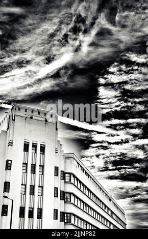 A vertical shot of a building under a cloudy sky in grayscale Stock Photo