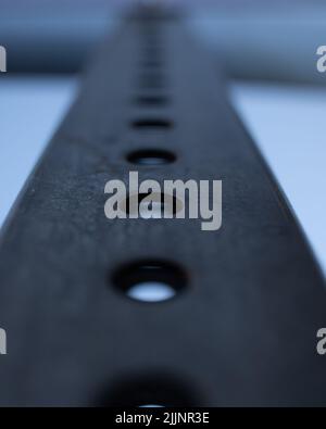 A vertical shot of a metal surface with holes on a blurred background Stock Photo