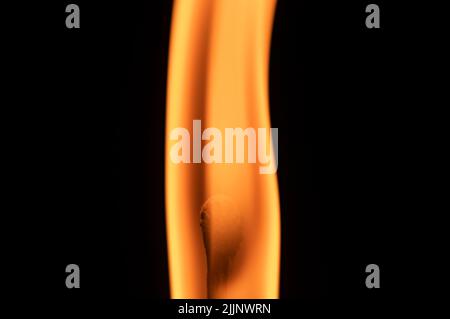 Flame from a burning match rises smoothly. On a black background with studio style lighting close up matchstick. Stock Photo