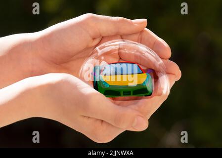 A modern car in a bubble in a person's hand - car insurance concept Stock Photo