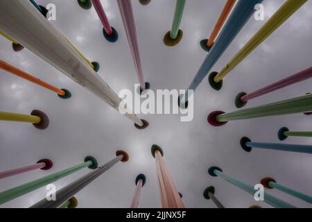 Milan, Italy - June 26, 2022: Below View of Colorful Poles with Cloudy Sky. Contemporary Art in Milan. Modern Installation in Lombardy. Stock Photo