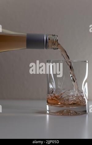 A vertical shot of an alcoholic drink being poured into a glass Stock Photo
