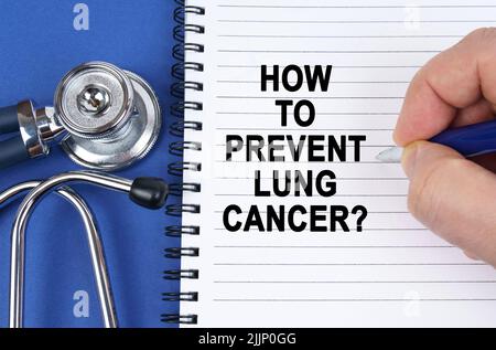 Medical concept. On a blue surface lies a stethoscope and a notebook in which it is written by hand - How to Prevent Lung Cancer Stock Photo