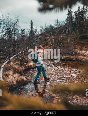 vertical shot of norwegian woman walking in clear water in norwegian autumn  forest Stock Photo