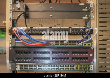 Patch panels installed in a network rack where LAN switches are installing Stock Photo