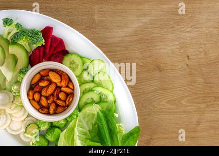 Various vegetables and nuts on wooden background top view with copy space Plate of fresh vegetarian food concept Stock Photo