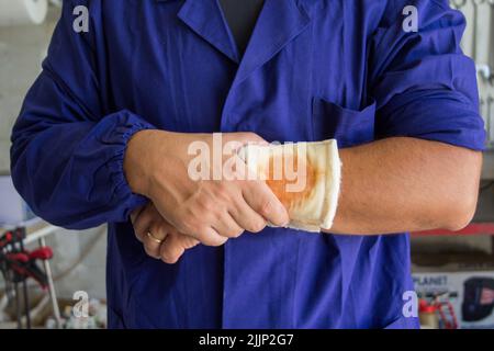 Image of a handyman with a bandaged wound on his arm. Reference to accidents at work Stock Photo