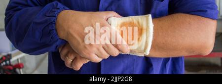 Image of a handyman with a bandaged wound on his arm. Reference to accidents at work. Horizontal banner Stock Photo