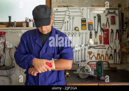 Image of a handyman with a bandaged wound on his arm. Reference to accidents at work Stock Photo