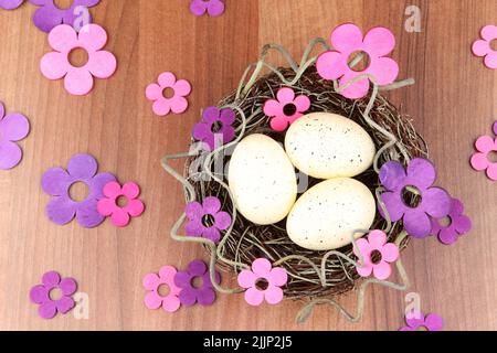A handmade Easter nest with eggs and flowers in lilac tones, on a wooden table Stock Photo