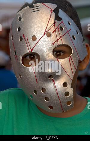 A vertical shot of a boy wearing a terror mask at a popular party in the city of Salvador, Bahia Stock Photo