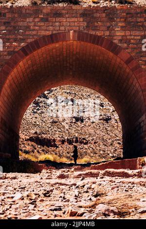 A beautiful view of a person under the stone bridge on a sunny day Stock Photo