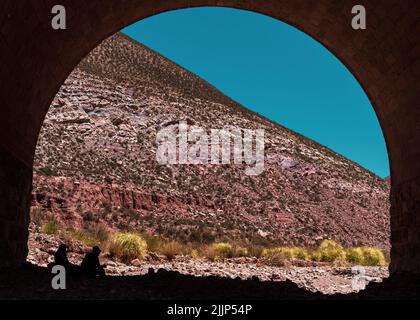 A beautiful view of a couple under the stone bridge on a sunny day Stock Photo