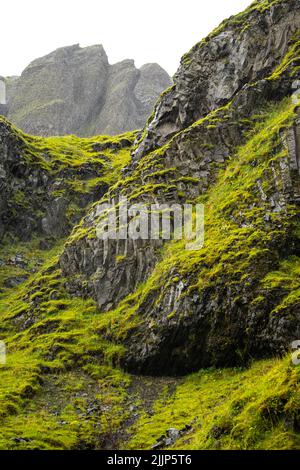 A view of massive black rocks covered with fresh green moss on a spring or summer day Stock Photo