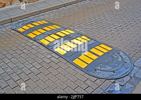 yellow speed delimiter as security sign on brick stone street, safety travel diversity Stock Photo