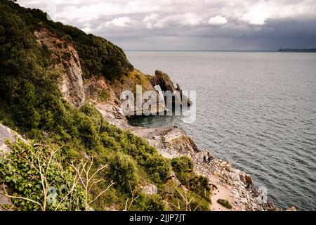 The London bridge arch and rocky green coast in Torquay, England, UK Stock Photo