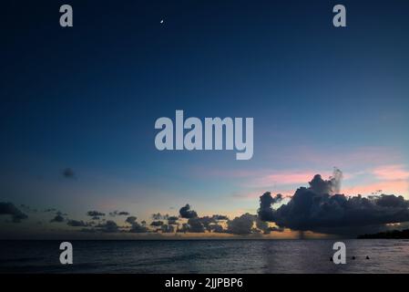 A beautiful scene of large water gray sea with dramatic clouds in the sunset sky on the horizon Stock Photo