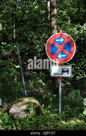 A road sign against a dense green forest Stock Photo