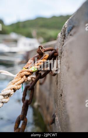 A vertical shot of a brown string with a rusty metal hanging on a stone on a blurred background Stock Photo