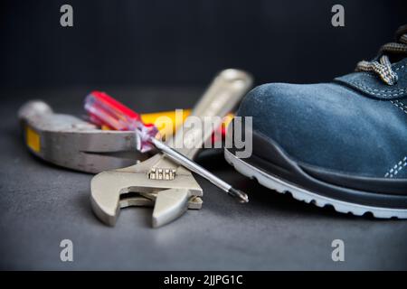 A closeup of metal tools placed next to a blue suede boot on a blurry background Stock Photo