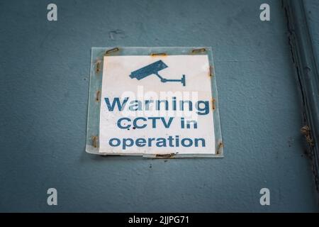 Warning - CCTV in operation, old weathered signage on a door in England, UK Stock Photo