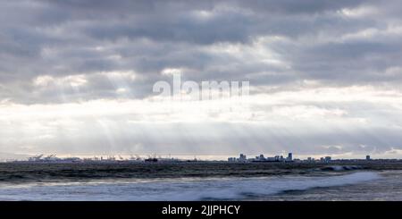 A panoramic landscape view of stony beach by majestic sea water and a blue sky on the horizon Stock Photo