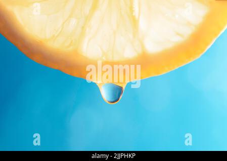 Slice of lemon isolated on blue background with water droplet waiting for drop Stock Photo