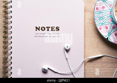Notebook lying on the table with white headphones and a cup of tea in a teacup, pink, office supplies Stock Photo
