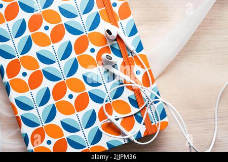 White headphones lying on the orange notebook Stock Photo