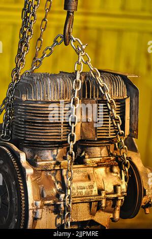 A closeup shot of a big machine motor with metal chains around it on a sunny day with blurred yellow background Stock Photo