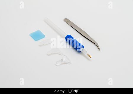 Stainless steel tweezers and pen with several heads for diamond painting on a white background. Stock Photo