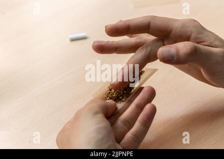 A close-up of a man's hands preparing marihuana joint Stock Photo