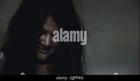 Scary ghost woman. Portrait of Asian ghost or zombie horror creepy scary have hair covering the face her eye at abandoned house dark tone, female make Stock Photo