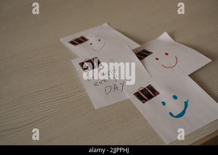 White sticky notes with smiley faces and a motivational quote on a wooden background Stock Photo